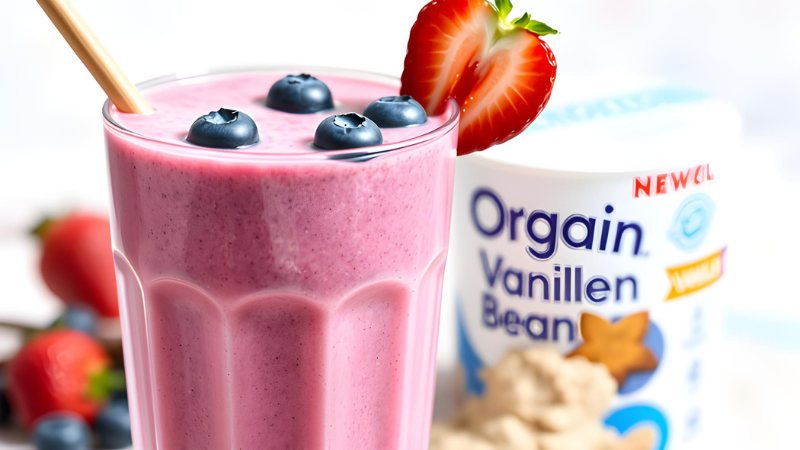 "Vanilla Berry Bliss Smoothie with Orgain Vegan Protein Powder in a glass with berries and bamboo straw."