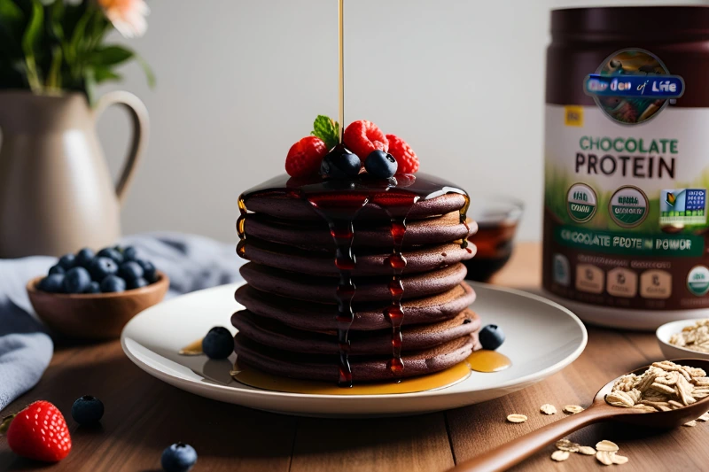 A stack of chocolate pancakes with berries, next to Garden of Life Chocolate Protein Powder and oats.